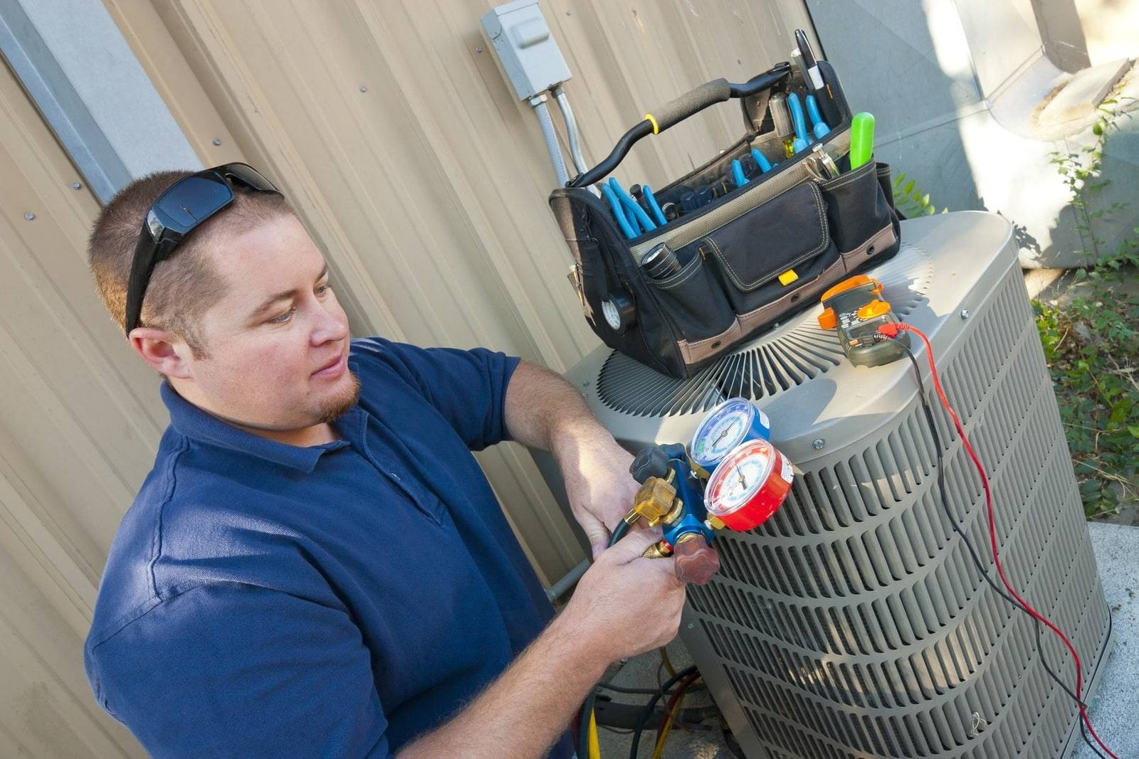 technician in blue uniform installing a new air conditioner