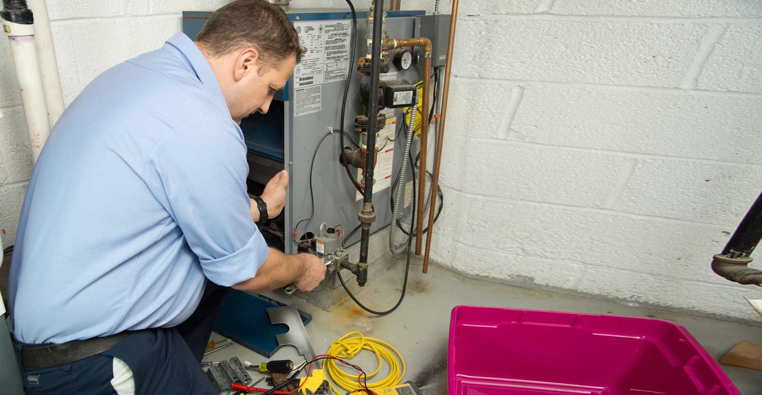 technician in blue uniform checking oil furnace